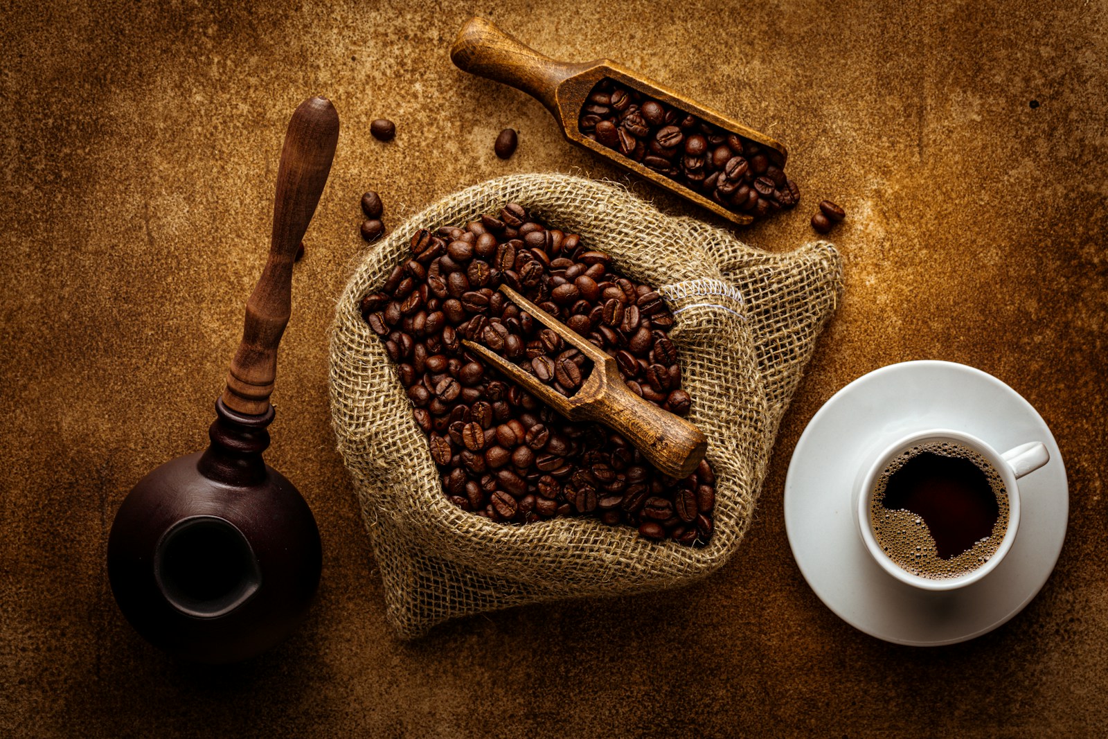 Grains de café torréfiés, sac en toile et cuillère en bois